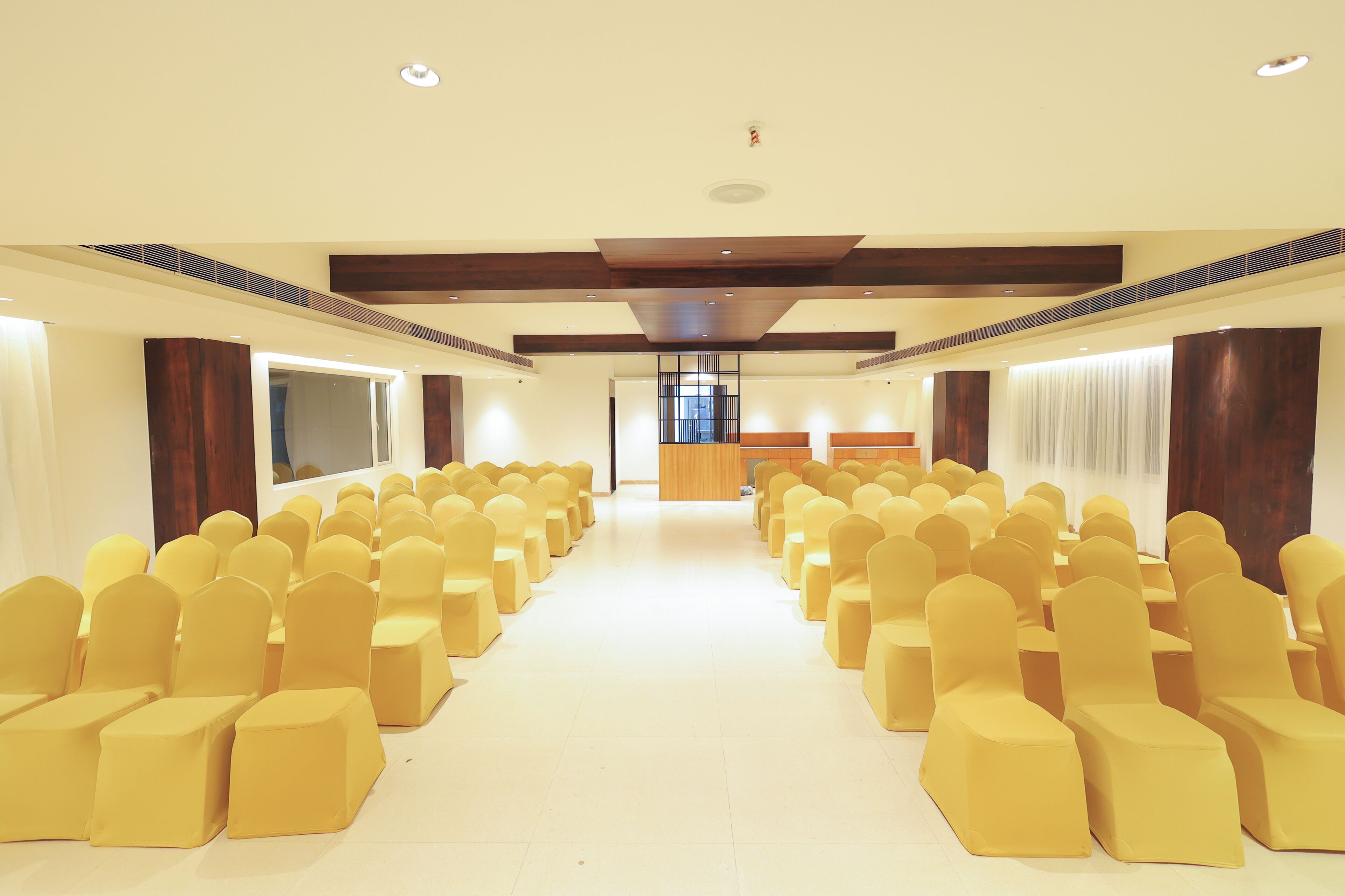 A conference room with rows of yellow chairs, a wooden podium, and a large window.