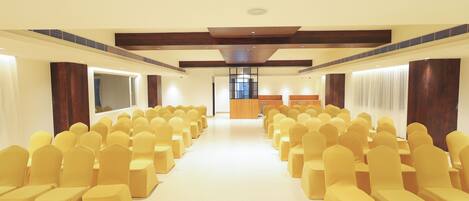 A conference room with rows of yellow chairs, a wooden podium, and a large window.