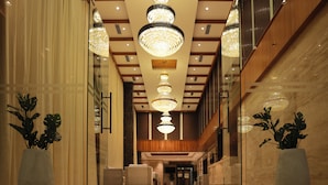 A spacious lobby with a high ceiling, large chandeliers, and potted plants. - Icon Grand Hotel by Bhagini (Bengaluru)