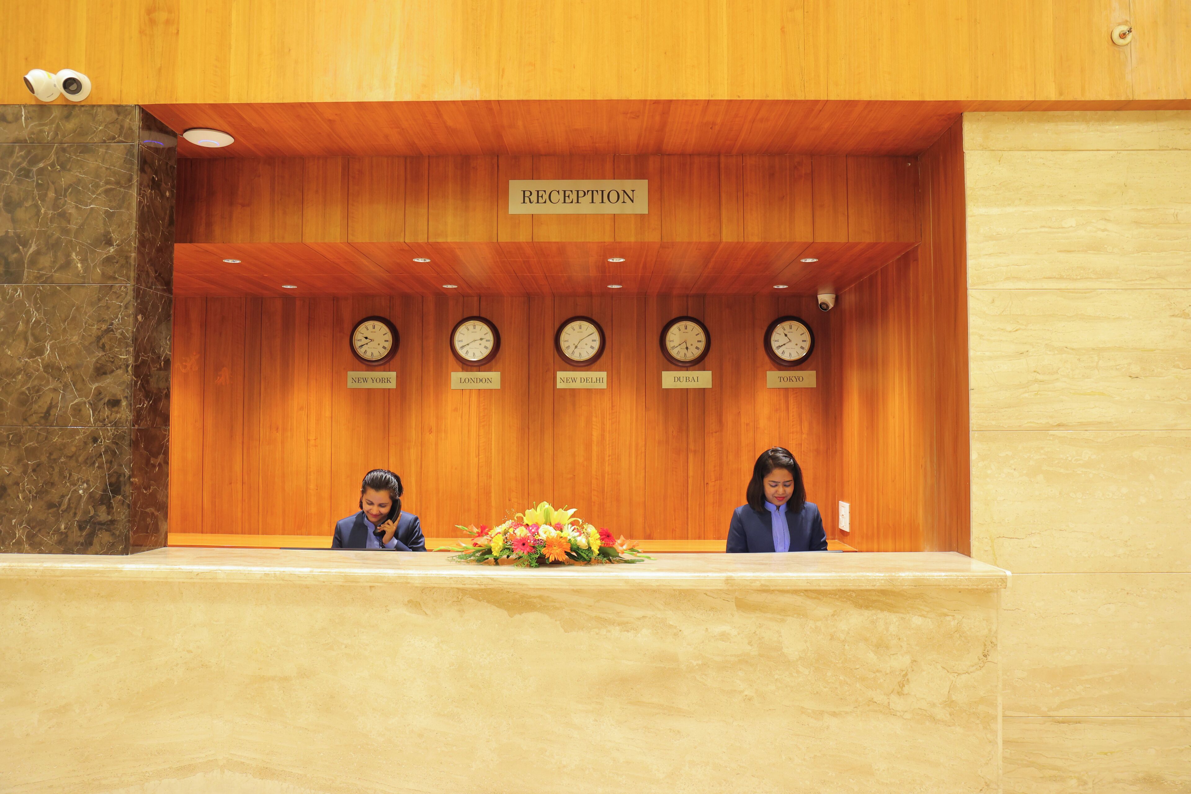 A reception area with a wooden ceiling, a reception desk, and clocks indicating different time zones.