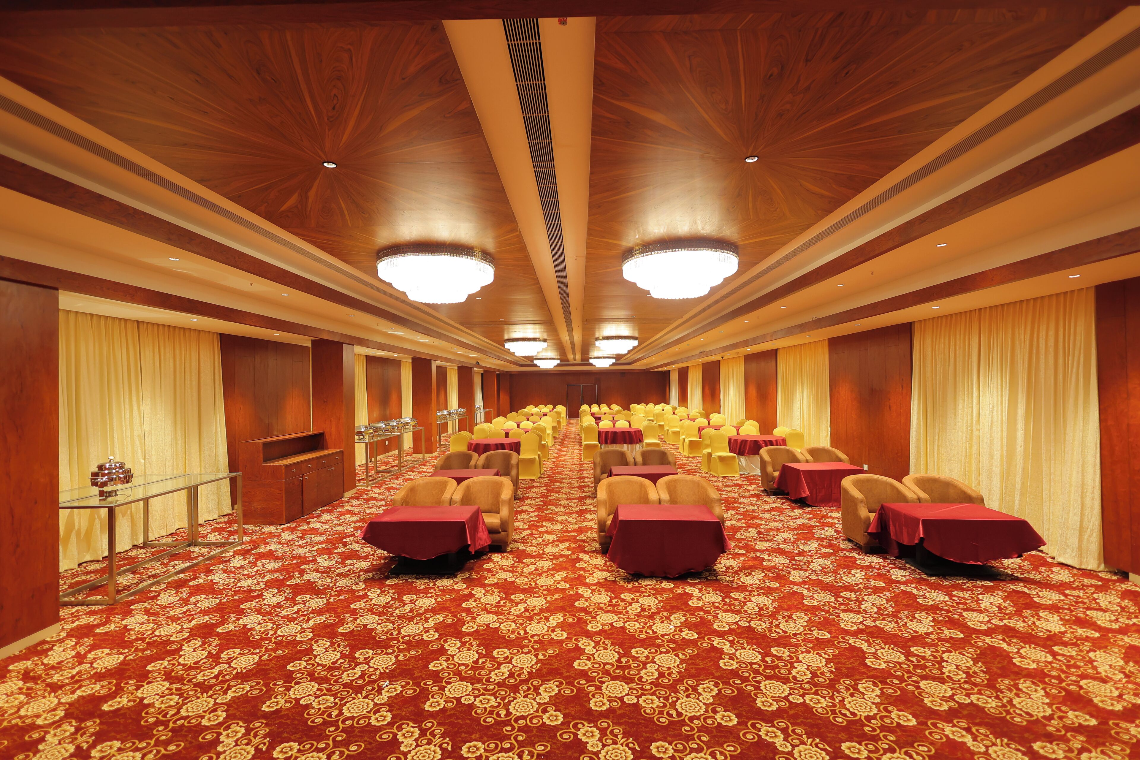 A conference room with rows of tables and chairs, wooden paneling on the walls, and a patterned carpet.