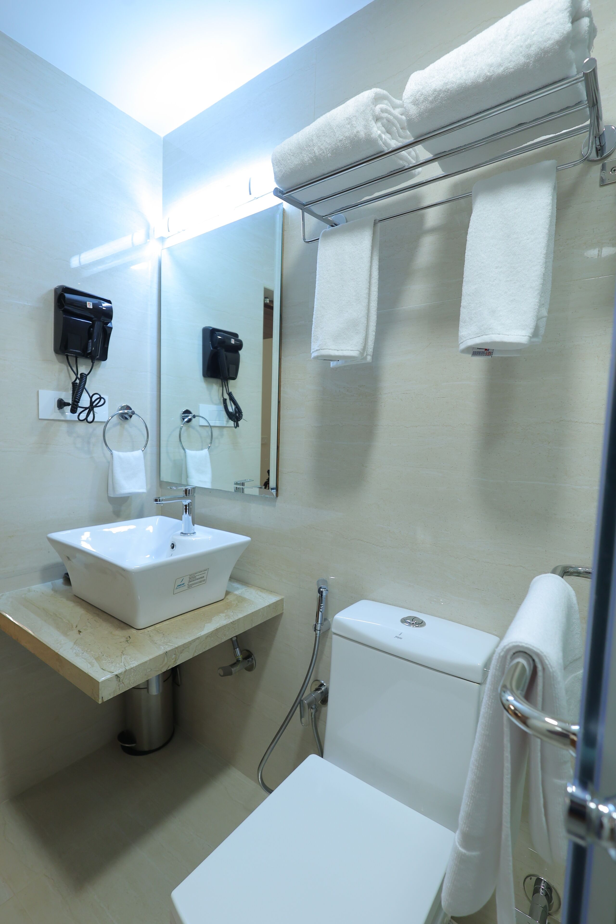Une salle de bain avec un lavabo blanc, un miroir, un porte-serviettes et des toilettes.