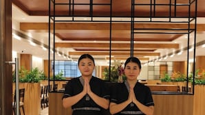 Two individuals in black uniforms standing in a reception area with wooden paneling and a modern design. - Icon Grand Hotel by Bhagini (Bengaluru)