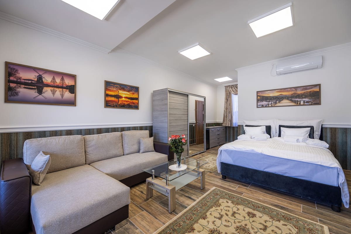 Une chambre à coucher moderne avec un lit, un canapé, une table basse en verre et une armoire.