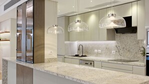 A modern kitchen with a marble countertop, stainless steel appliances, and pendant lighting. - VESTA - Heliopolis Residence (Cairo)