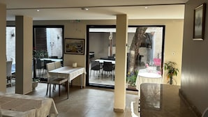 A dining area with tables and chairs, a painting on the wall, and a view of the outside through a glass door. - Demirci Otel (Bursa)