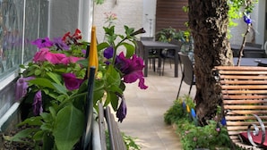 A patio area with a wooden bench, a cactus planter, and a table with chairs. - Demirci Otel (Bursa)