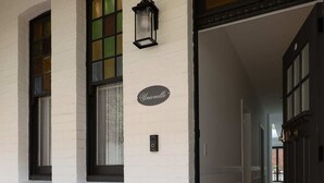 Ein weißes Gebäude mit einer schwarzen Tür und einer Fußmatte mit dem Schriftzug "Hello" am Eingang.