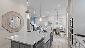 A modern kitchen with a central island, stainless steel appliances, and pendant lighting.