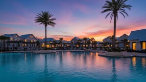 A resort with multiple buildings, a swimming pool, and palm trees.