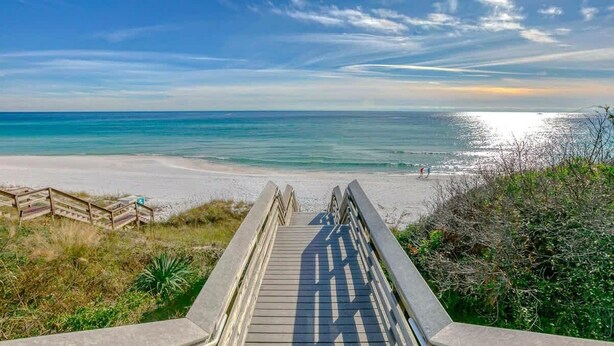 A wooden boardwalk leading to a beach with a clear view of the ocean.