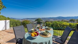 Une table installée à l’extérieur, offrant une vue pittoresque, entourée de chaises et d’une clôture.