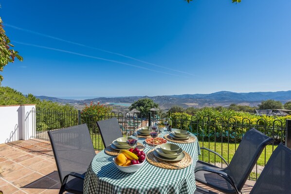 A table set outdoors with a scenic view, surrounded by chairs and a fence.