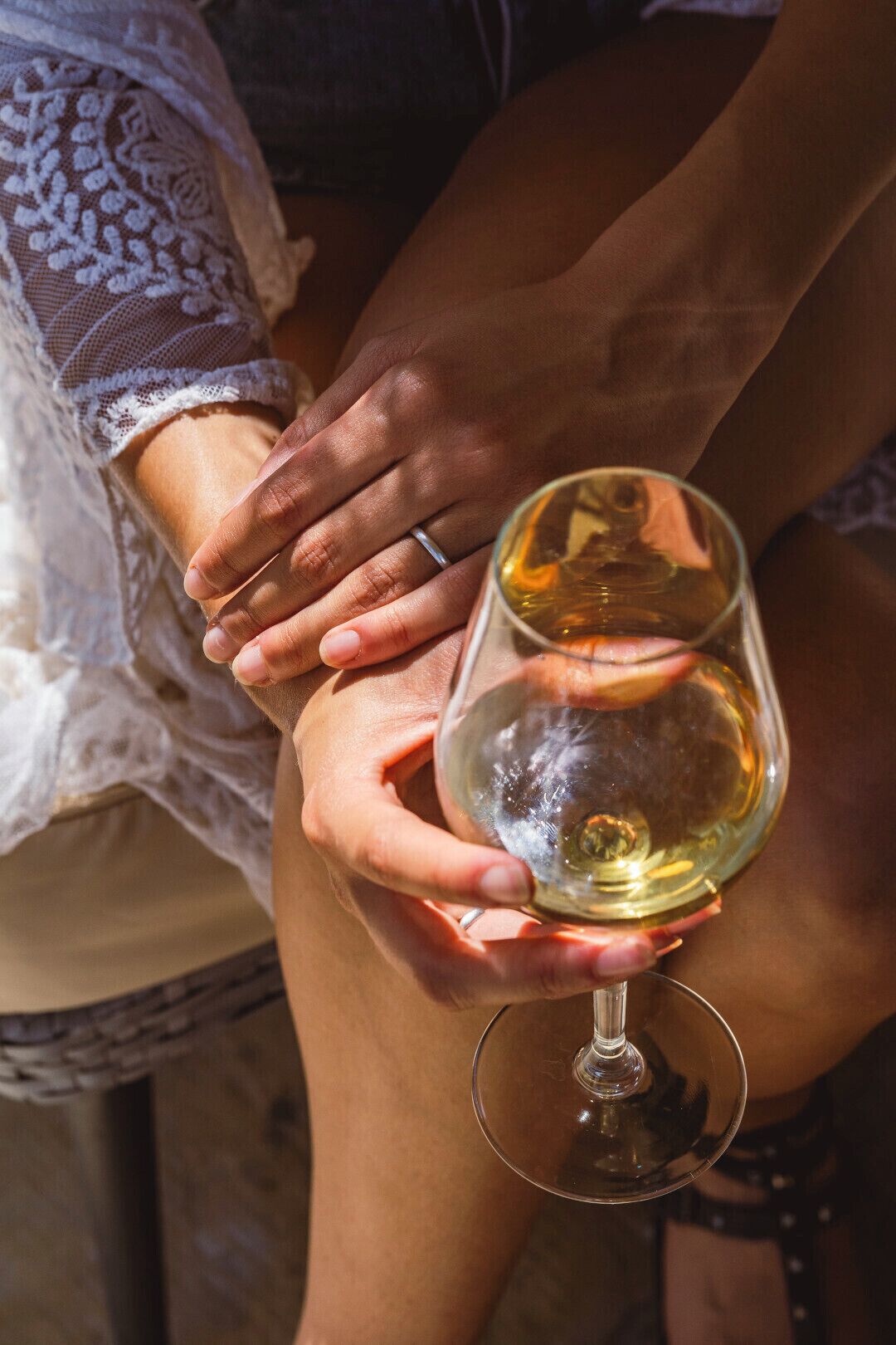 A close-up of hands holding a wine glass.