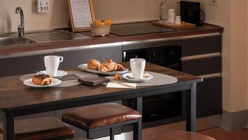 Cozinha moderna com ilha central, banquetas, máquina de café e cardápio emoldurado na parede.