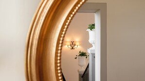 A mirror reflecting a staircase with a wall-mounted light fixture and a potted plant. - Villa Erbaia Relais de Charme (Barberino di Mugello)