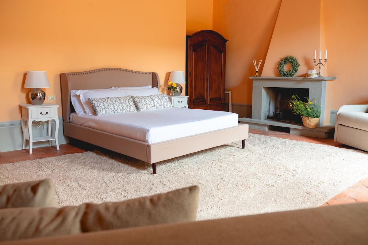 Une chambre à coucher avec un grand lit, des tables de chevet, une commode et une cheminée.