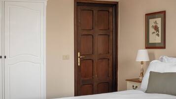 Une chambre à coucher avec un lit, une armoire, une porte, une table de chevet avec une lampe et un tableau encadré au mur.