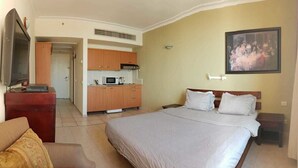 A hotel room with a bed, a TV, a kitchenette, and a painting on the wall. - Beautifull apartments by the sea (Haifa)