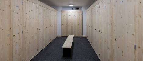 A locker room with wooden lockers, a bench, and a carpeted floor.
