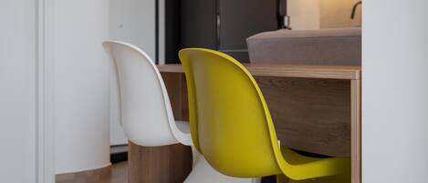 A modern dining area with a wooden table and two chairs, one white and one yellow.