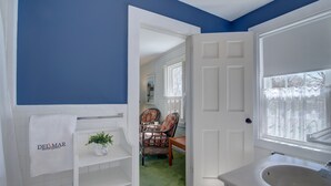 A bathroom with a white bathtub, a sink, and a towel rack with a 'Delmar Vacation Rentals' sign. - Walk to Downtown Chatham, Steps to Beach! (Chatham)