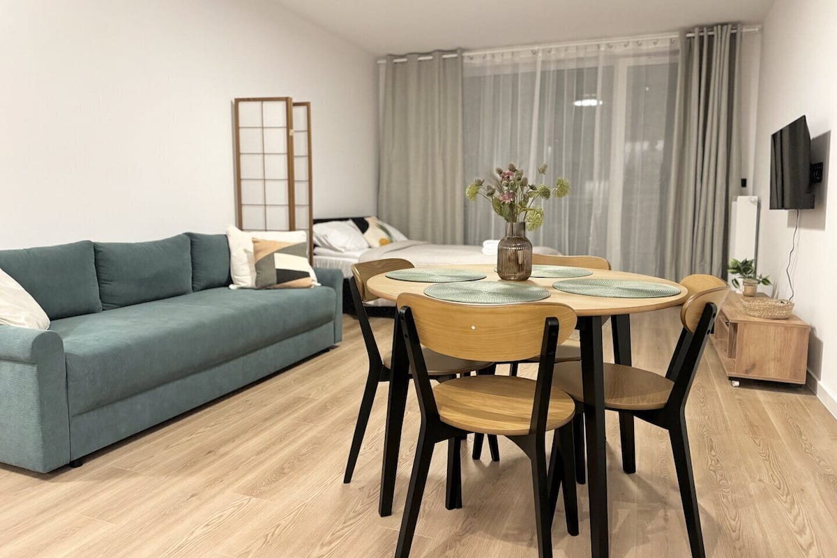 A modern living room with a sofa, dining table, chairs, and a TV.