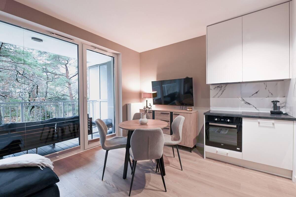 A modern kitchen with a built-in oven and a dining area with a round table and chairs.