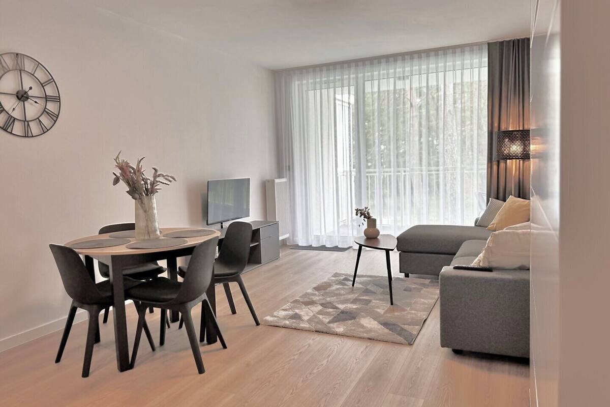 A modern living room with a dining area, a sofa, and a TV.