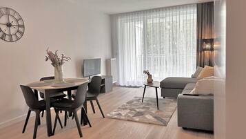 A modern living room with a dining area, a sofa, and a TV.