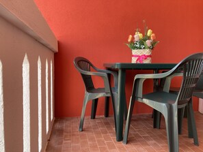Un muro rosso, un tavolo con sedie e un bouquet di fiori.