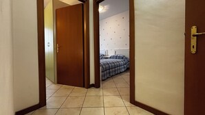 A hallway with a wooden door leading to a room with a bed and a wall decorated with heart patterns. - Comfortable flat in Bibione - Beahost (Rosolina Mare)