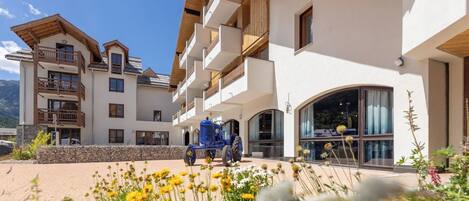 A multi-story hotel with balconies, a covered outdoor area, and a vintage blue tractor parked in front.