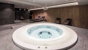 A modern indoor swimming pool with a hot tub, lounge chairs, and a tiled floor. - TERRESENS - Hôtel Le Cristal Lodge (Saint-Chaffrey)