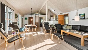 Un'ampia zona giorno con soffitto alto, un tavolo da pranzo e comodi posti a sedere.