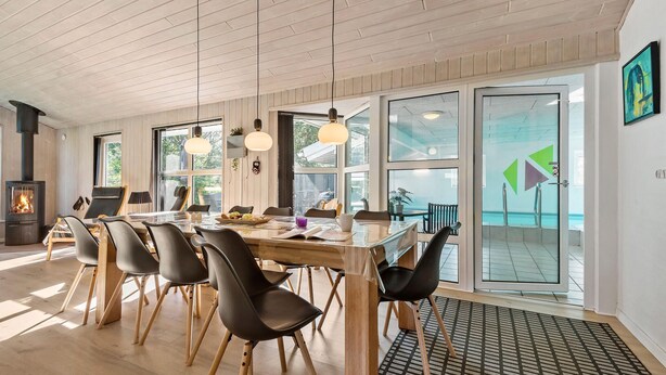 Una sala da pranzo moderna con tavolo e sedie in legno, un camino e ampie finestre.