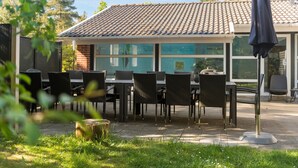 Una terrazza esterna con tetto in tegole, mobili in vimini e chiusura in vetro.