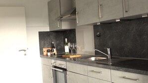 Una cocina moderna con armarios grises, un lavamanos de acero inoxidable y un horno empotrado.