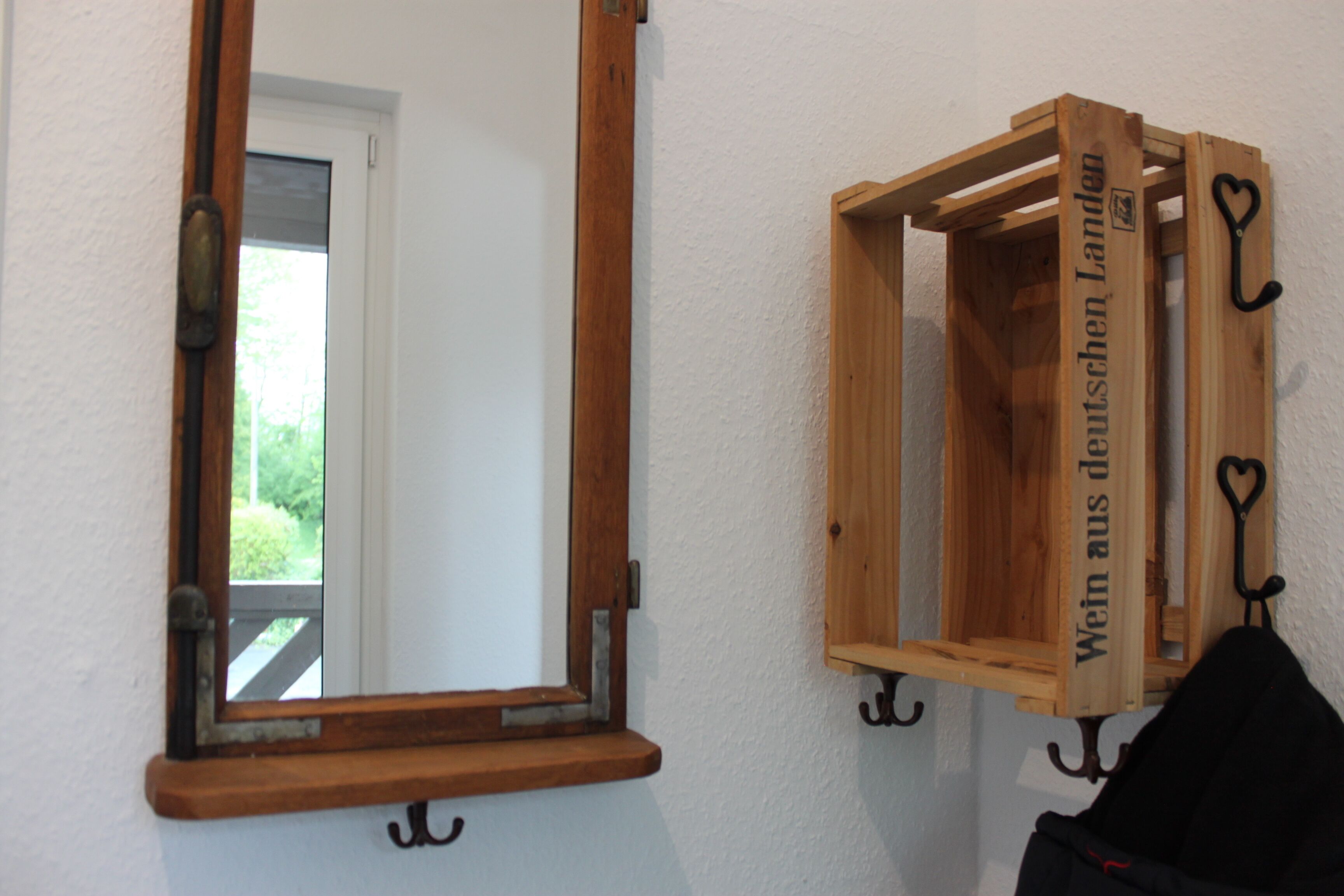 Un meuble en bois muni de crochets et d’un miroir.