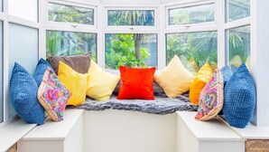 Un invernadero con zona de estar con bancos, ventanas amplias y vistas a follaje exterior.