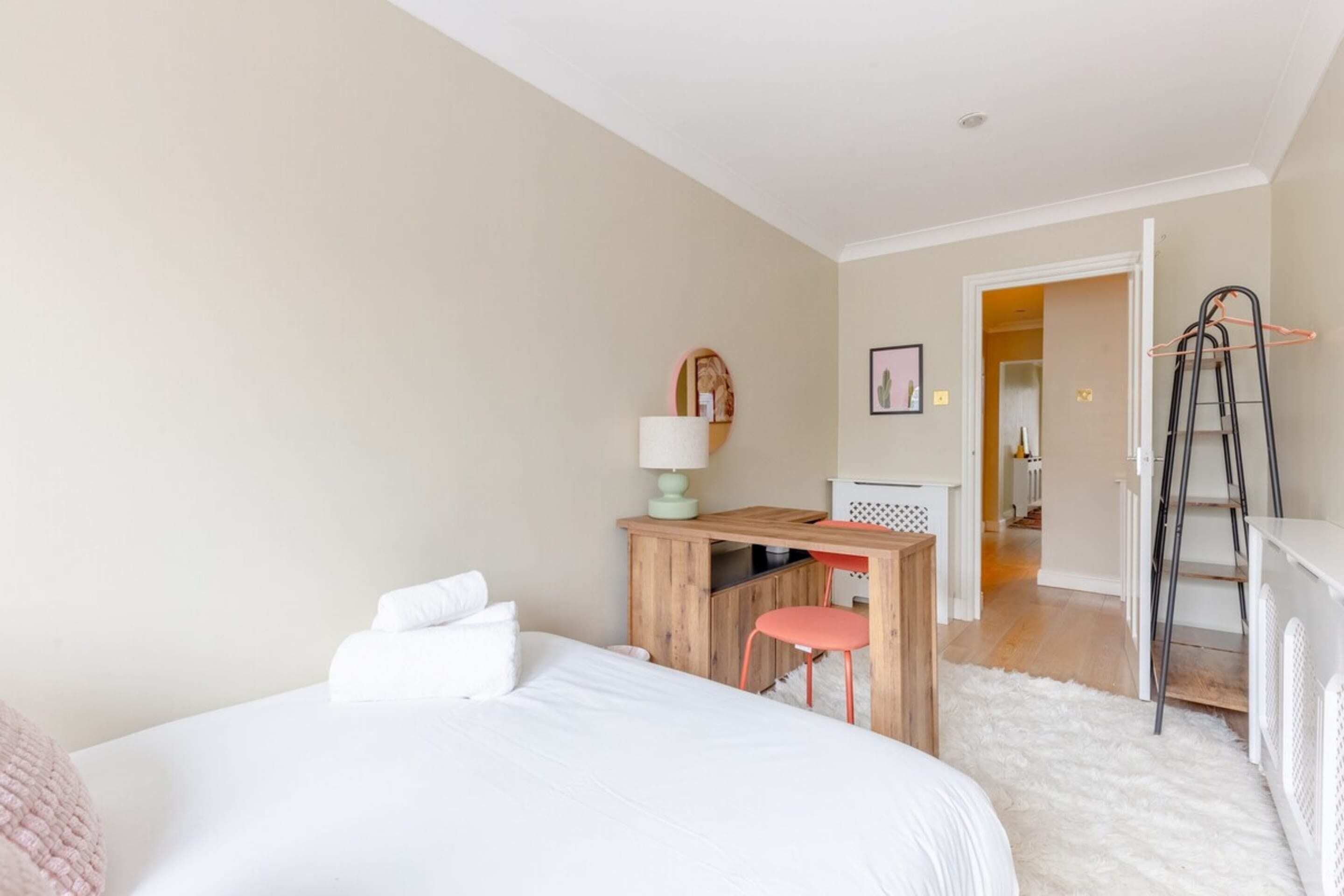 A bedroom with a bed, a desk, a chair, a lamp, and a ladder.