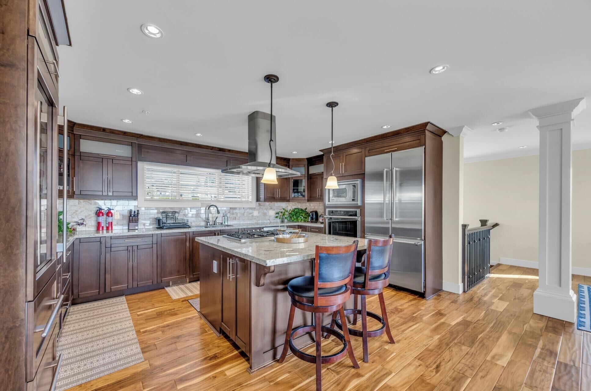 Una cocina moderna con armarios de madera, electrodomésticos de acero inoxidable y una isla central con taburetes de bar.
