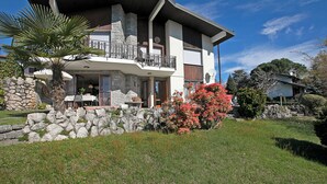 A two-story house with a balcony, stone walls, and a well-maintained lawn. - Il Poggio Radioso Lake View & Garden (Massino Visconti)