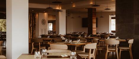 Un restaurant spacieux, doté de nombreuses tables et chaises, d’une grande horloge murale et d’un éclairage suspendu.