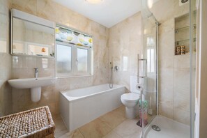 A modern bathroom with a bathtub, toilet, and glass-enclosed shower. - A Delightful 4-bedroom Home With a Private Garden (London)