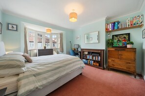 A bedroom with a bed, a desk, a dresser, and a bookshelf. - A Delightful 4-bedroom Home With a Private Garden (London)