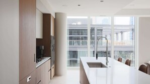 A modern kitchen with a large island, built-in appliances, and large windows offering city views.