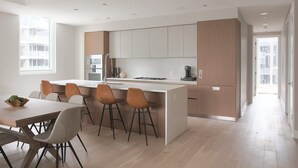 Une cuisine moderne dotée d’un îlot central, de tabourets de bar et d’une table à manger.