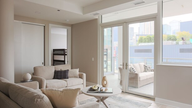 Un salon moderne comprenant un canapé, une table basse et une grande porte-fenêtre coulissante donnant sur un espace de détente extérieur.