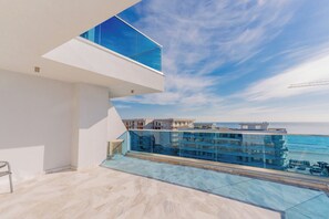 A modern balcony with a glass railing overlooking a body of water and buildings. - Wave 4 Residence (Navodari)